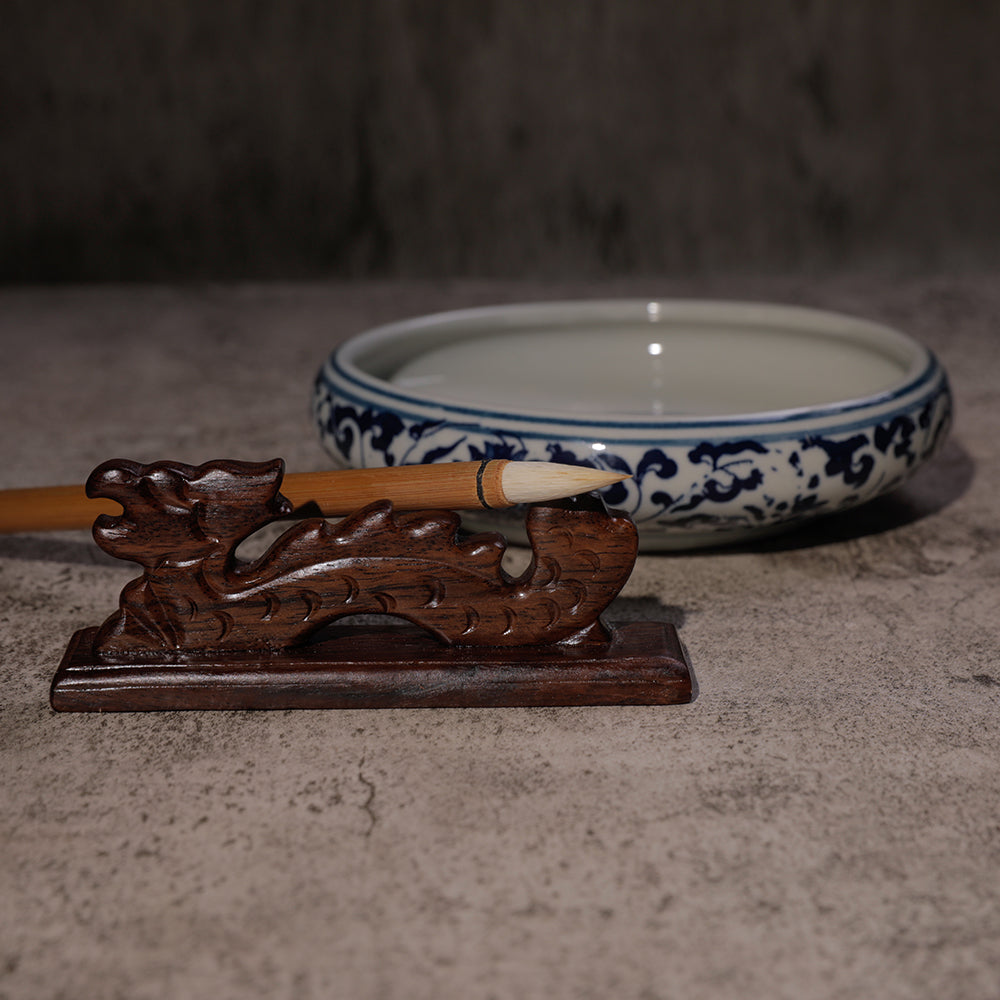 Ceramic Chinese water bowl with blue decorative pattern, Chinese fineline sumi brush resting on a wooden dragon brush rest