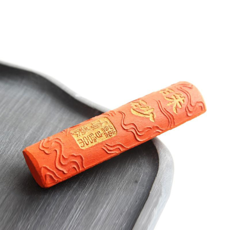Japanese Calligraphy and Sumi Ink Stick in red color with cinnabar pigment, decorated with manufacturer's name in golden lettering and a crouching dragon on the other side