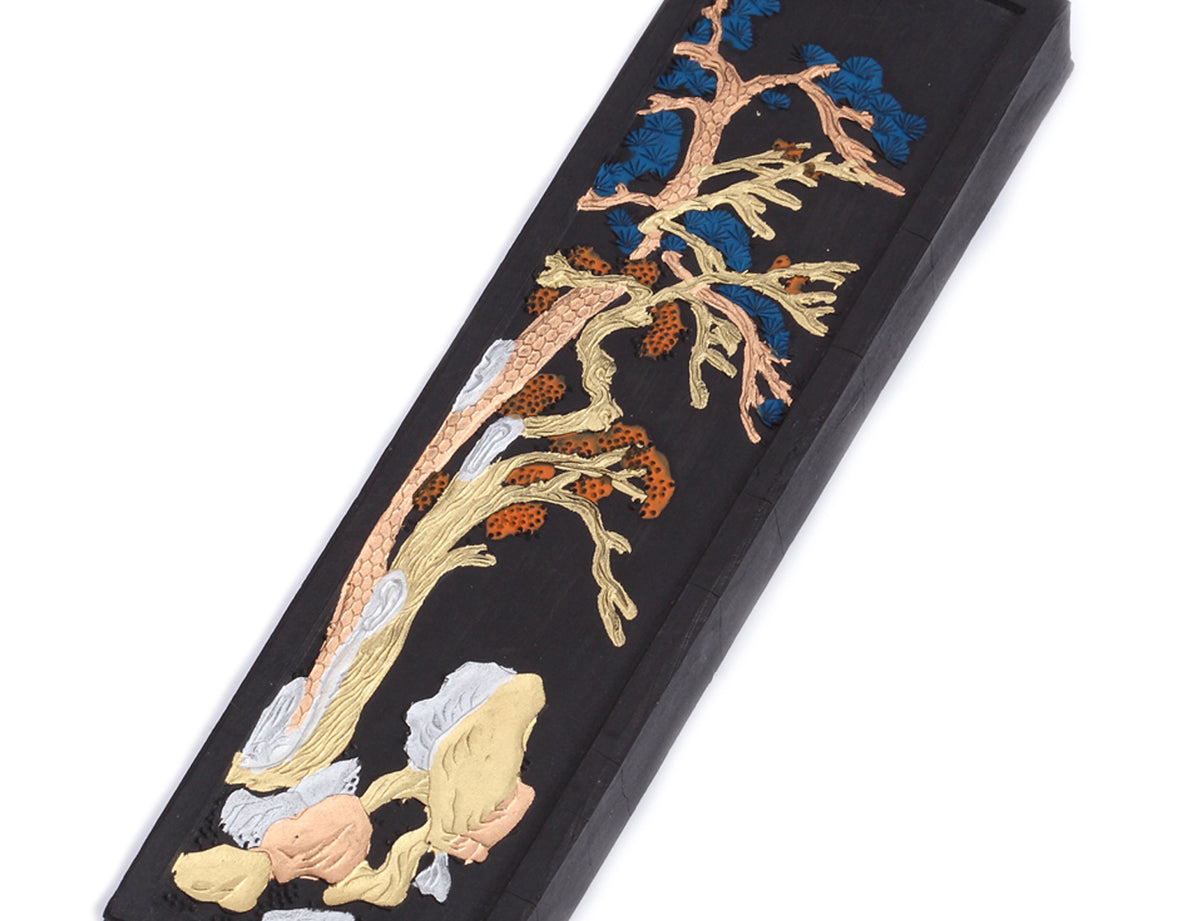 Zoom closeup view of Japanese calligraphy and sumi ink stick used to grind ink with an ink slab - black color, golden decorative print