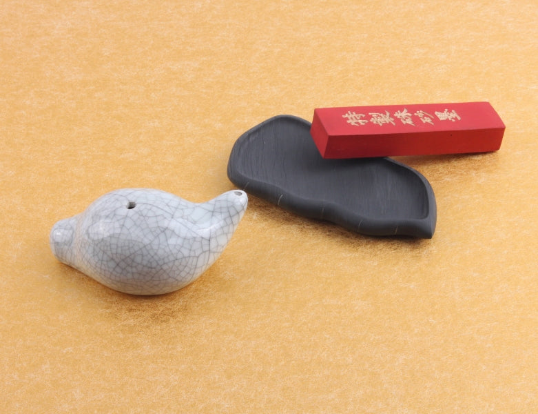 Traditional oriental ink slab and ink stone with Chinese characters displayed beside calligraphy accessory baby snali water dropper for brush painting