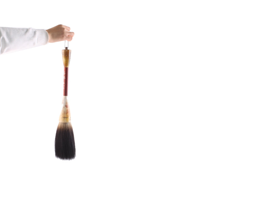 Large Chinese bear hair bristle tip calligraphy, sumi and shodo brush held on an outstretched hand to display and compare its size and huge dimensions.