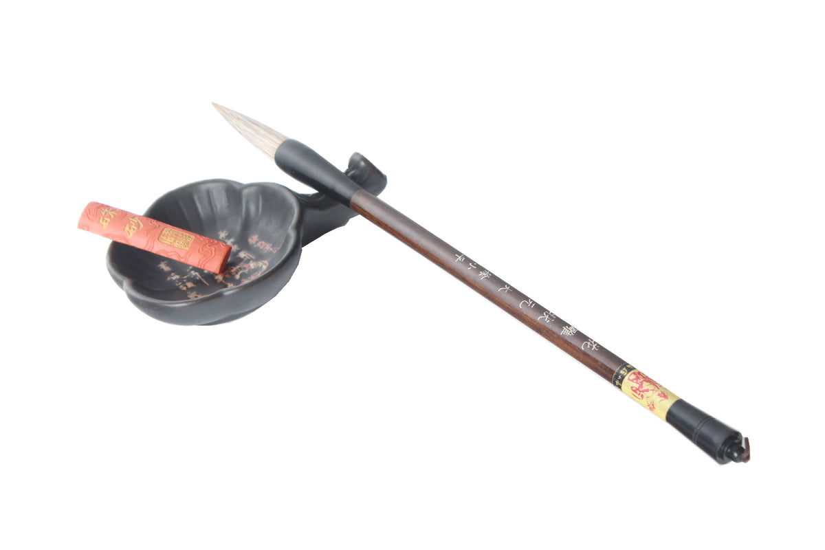 An ink stick &amp; a Chinese calligraphy brush resting on a plum flower shaped ink well.