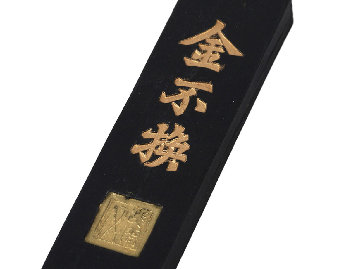 View of the back of a Chinese practice calligraphy, shodo, kanji and sumi ink stick with the manufacturer name carved into the black body of the ink stick.
