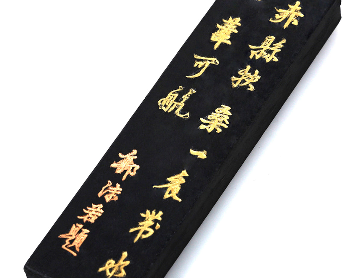 Closeup view on the gold-painted Chinese inscriptions on a Chinese Tang Mo ink stick used for Sumi, Fineline, Gongbi and calligraphy