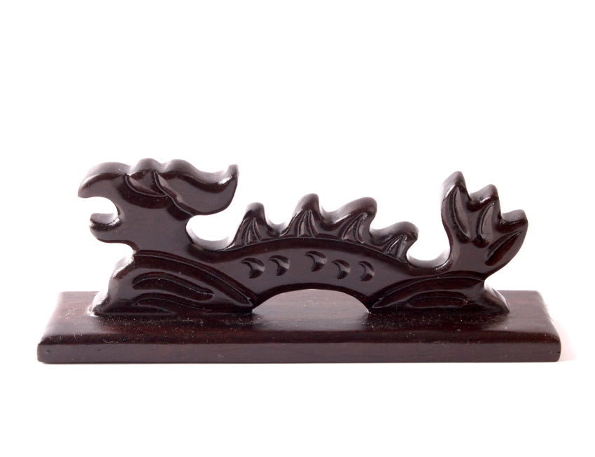 Detail close-up frontal view of an oriental dragon-shaped wooden brush rest for thin an longish brushes