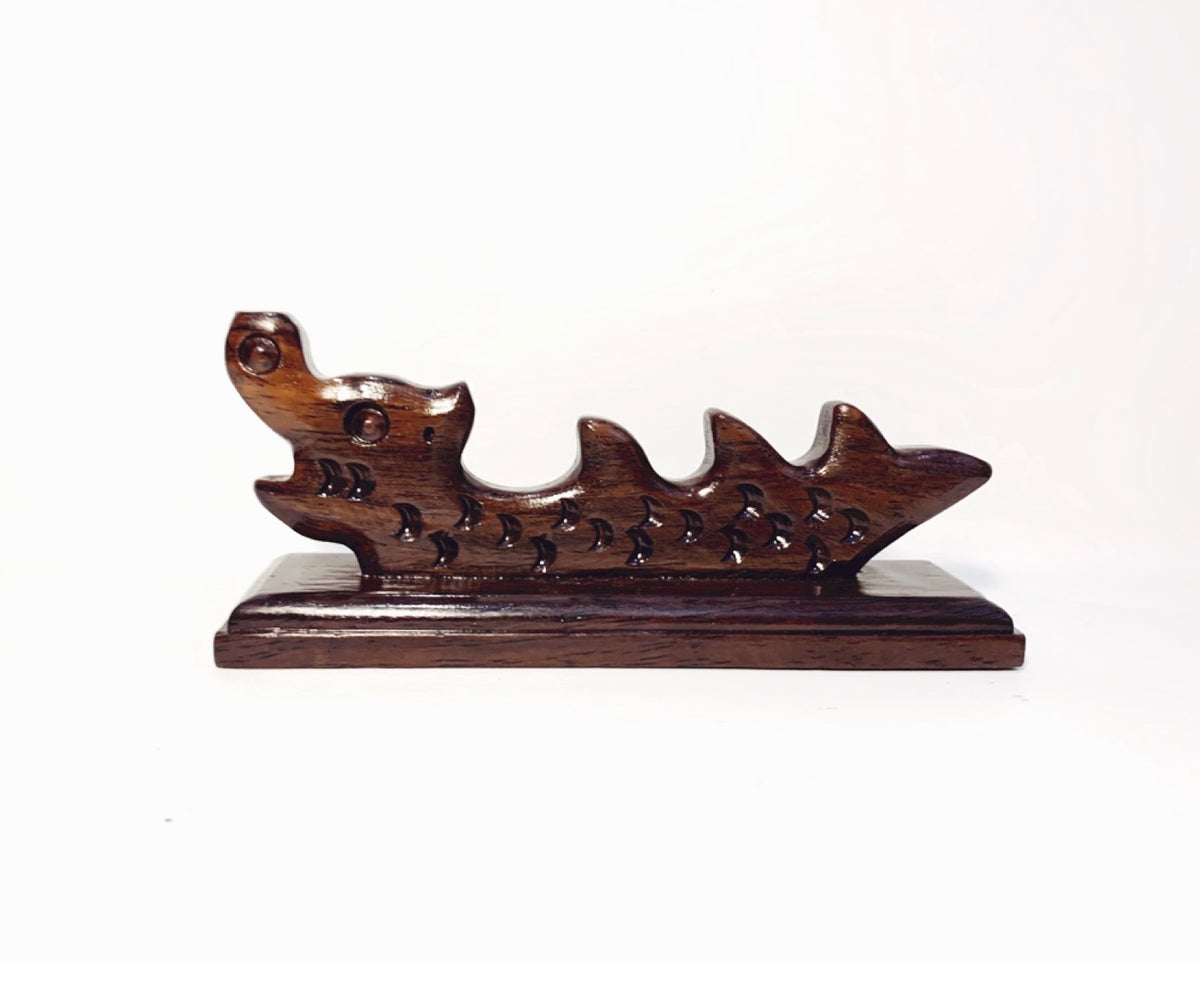 Detail close-up frontal view of an oriental dragon-shaped wooden brush rest for thin an longish brushes