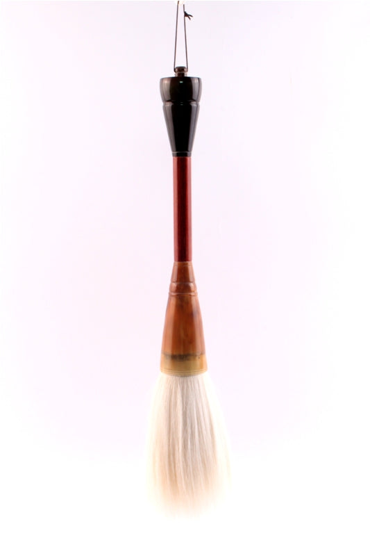 Picture of a very large Chinese artist goat hair brush with its 6 inch long white bristles hanging down to display their characteristics and dimension. 