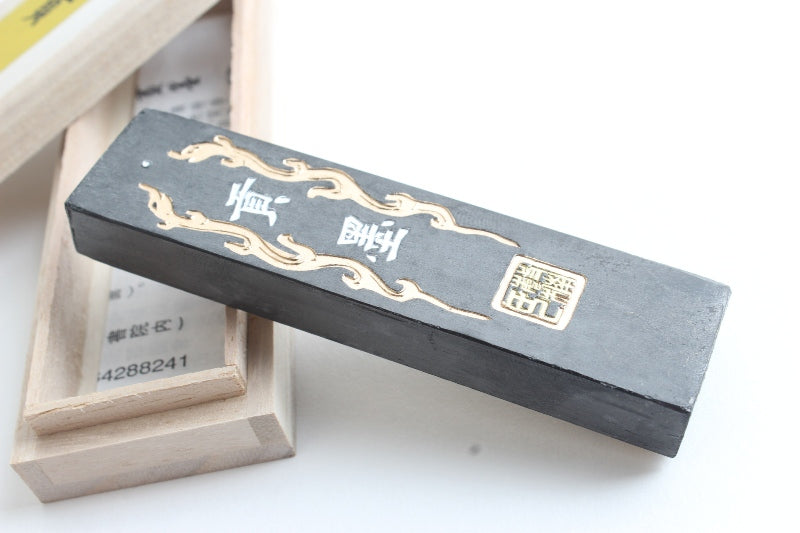 Chinese practice ink stick with hand painted characters and ornaments in gold and yellow on its black square body - for intermediate sumi and calligraphy practicioners or as premium practice ink stick