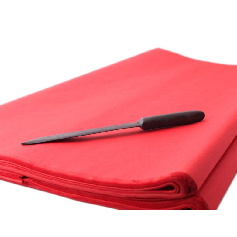 Golden sumi and calligraphy rice paper with dark hand carved rosewood cutting knife positioned on top